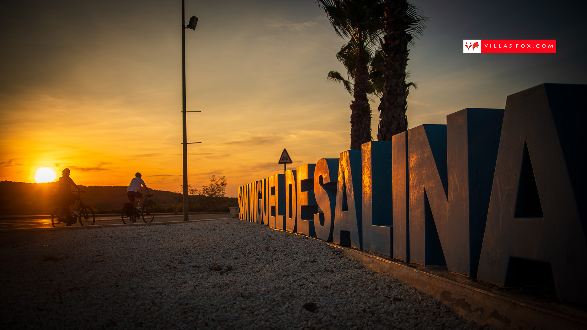 San Miguel de Salinas cyclists and town sign at sunset San Miguel de Salinas cyclists and town sign at sunset